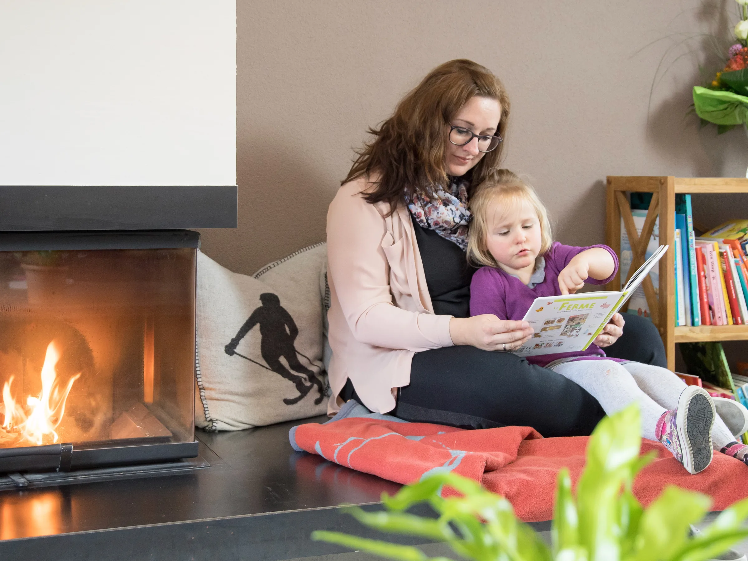 Familie beim gemeinsamen Lesen in einem Gastauer Wohnbereich am Kamin